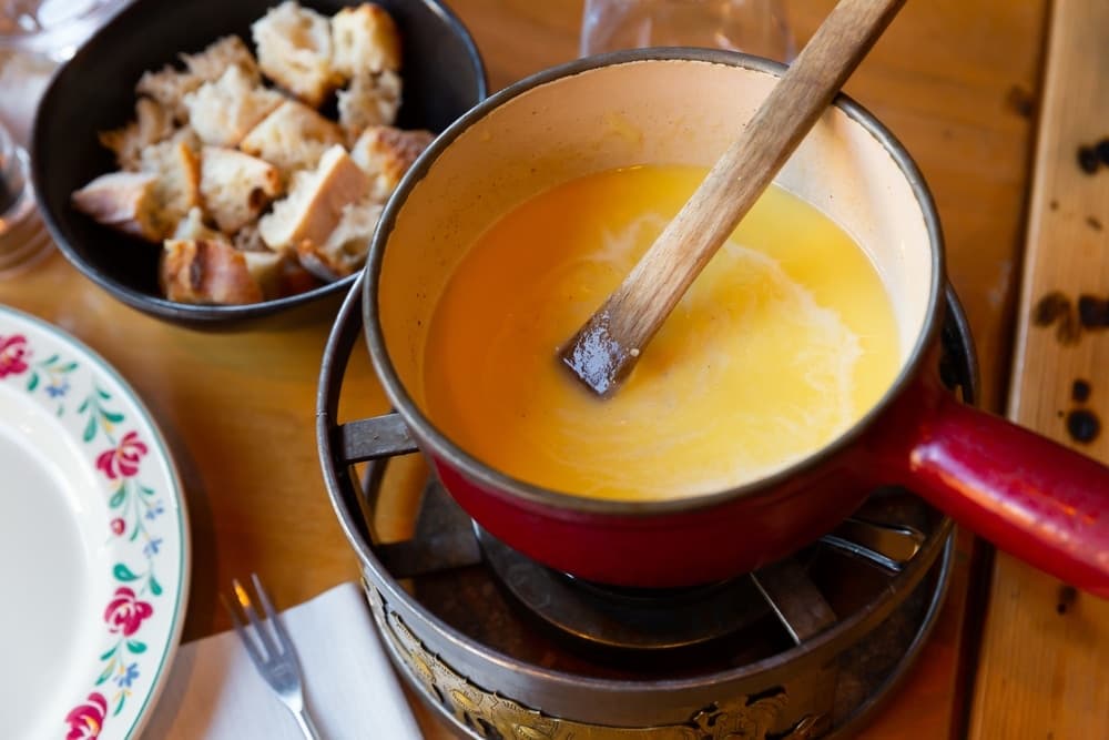 Fondue savoyarde aux trois fromages servie dans un caquelon avec des morceaux de pain