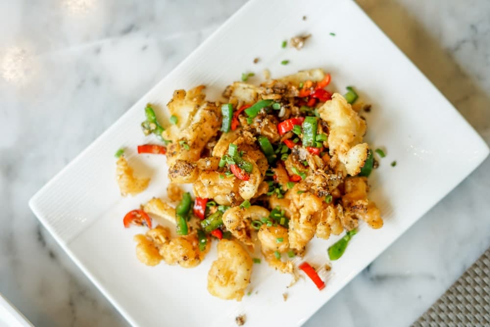 Jiao Yan You Yu servi dans une assiette, composé de calamars croustillants assaisonnés au sel et au poivre, une spécialité emblématique de la cuisine cantonaise.