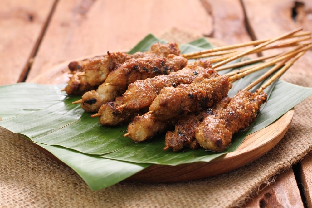 Brochettes de sate ayam sur une fueuille de banane.