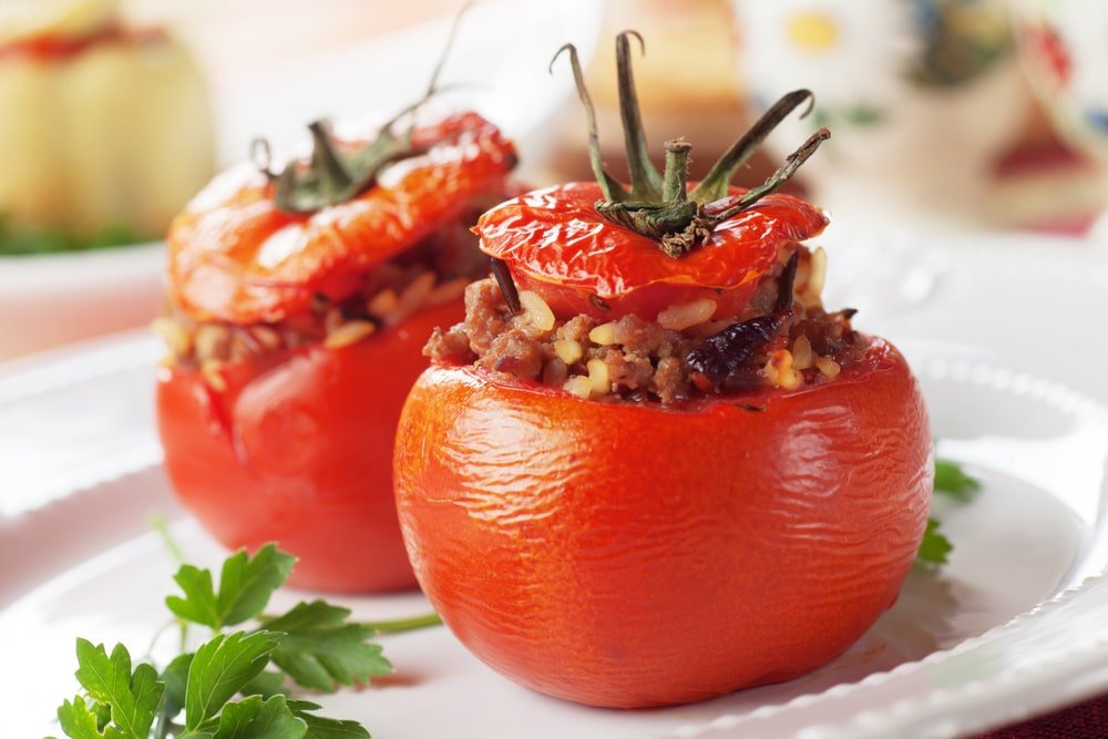 Deux tomates farcies servies sur une assiette.