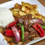 Assiette de lomo saltado péruvien accompagné de frites et de riz blanc