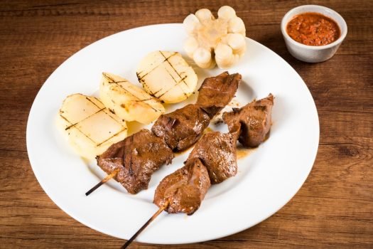 Brochettes d'anticuchos accompagnés de pommes de terre et du maïs.